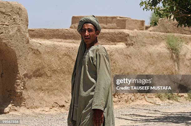 An Afghan boy looks on while US soldiers from Bravo Troop 1-71 CAV walk on patrol in Belanday village, Dand district in Kandahar on May 15, 2010....