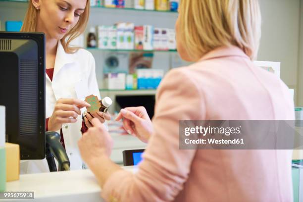 pharmacist advising woman in pharmacy - westend61 stockfoto's en -beelden