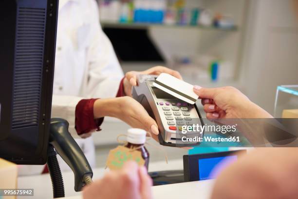 customer paying cashless with credit card in a pharmacy - westend61 stockfoto's en -beelden