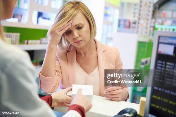 pharmacist advising woman in pharmacy - unhappy customer stock pictures, royalty-free photos & images