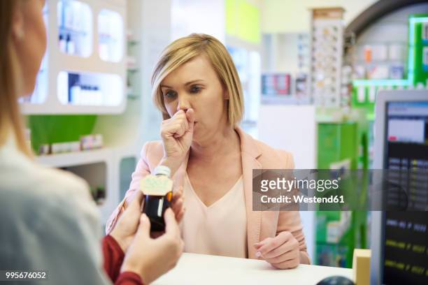 pharmacist selling cough syrup to woman in pharmacy - westend61 stockfoto's en -beelden