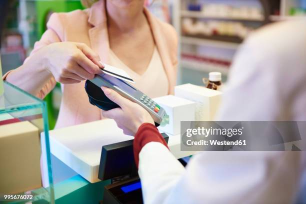 customer paying cashless with credit card in a pharmacy - nyckelkortläsare bildbanksfoton och bilder