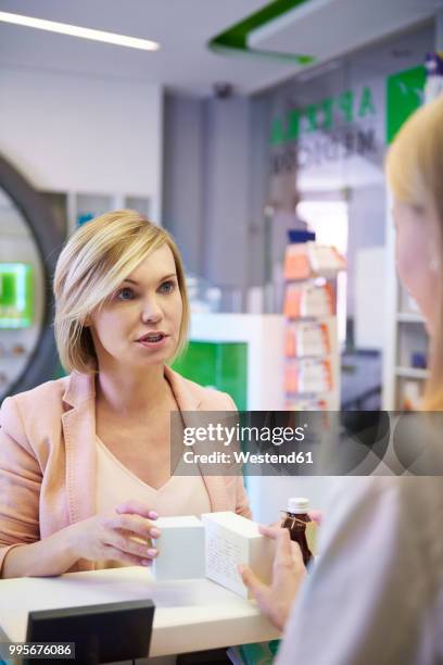 woman discussing product with pharmacist in pharmacy - westend photos et images de collection