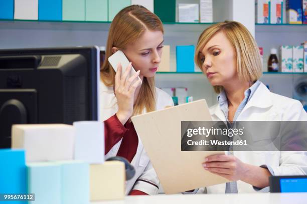 two pharmacists at cabinet in pharmacy - westend61 stockfoto's en -beelden