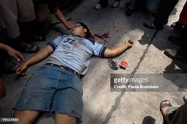 Red shirt protesters cover the face of a man killed by Thai military as the violence in central part of the city escalates on May 15, 2010 in...