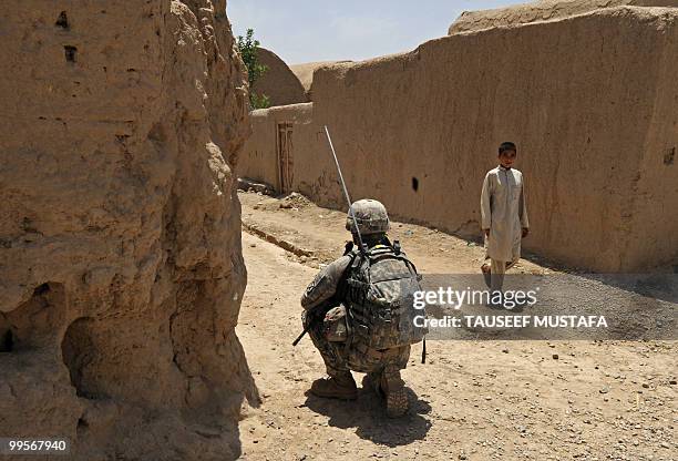 An Afghan walks by as a US soldier from Bravo Troop 1-71 CAV patrols in Belanday village, Dand district in Kandahar on May 15, 2010. NATO and the...