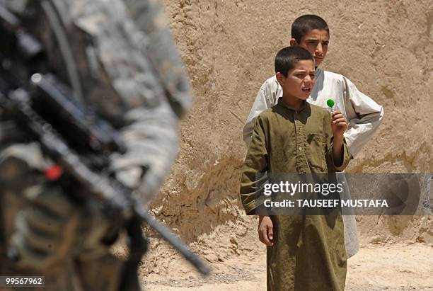 Afghan boys walks by as a US soldier from Bravo Troop 1-71 CAV patrols in Belanday village, Dand district in Kandahar on May 15, 2010. NATO and the...