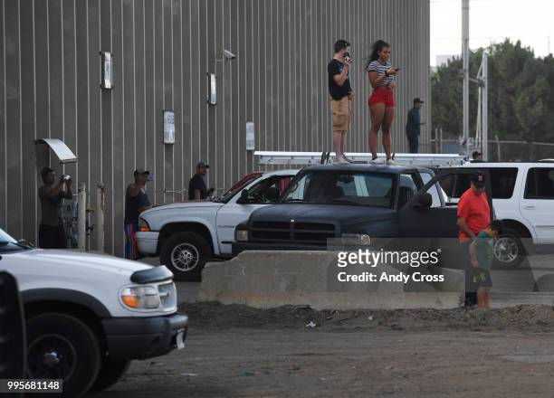 Onlookers get a higher angle on a fire in a large pile of crushed vehicles near 5600 York St. July 10, 2018.