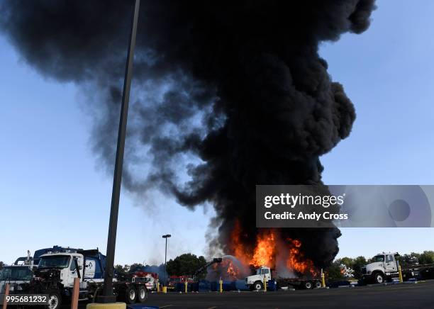 Black plume of smoke rises from a fire in a large pile of crushed vehicles near 5600 York St. July 10, 2018.