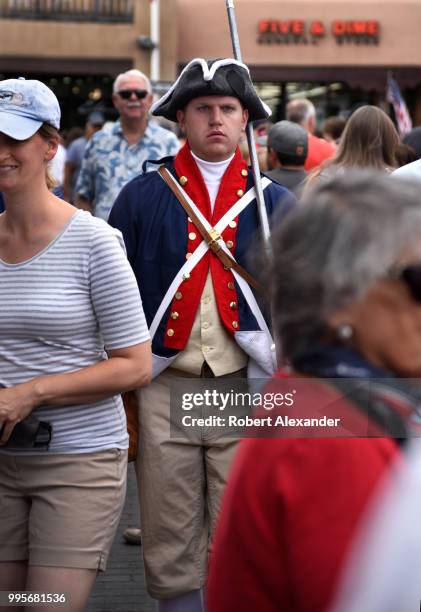 Man wearing a homemade Revolutionary War uniform and carrying a wooden rifle mingles with the crowd and poses for photographs at a Fourth of July...