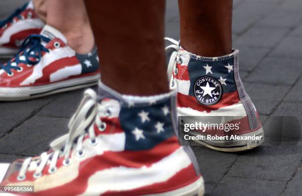 Man and woman wear 'stars and stripes' Converse Chuck Taylor All Star high top shoes as they enjoy a Fourth of July holiday celebration in Santa Fe,...