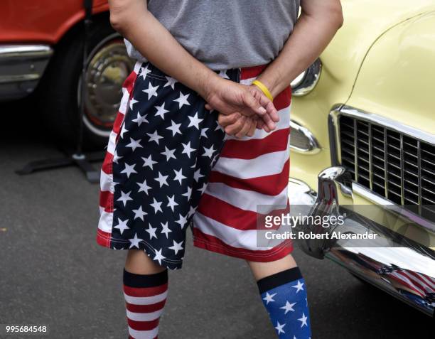 Man wears 'stars and stripes' shorts and sock as he enjoys a Fourth of July classic car show and holiday celebration in Santa Fe, New Mexico.