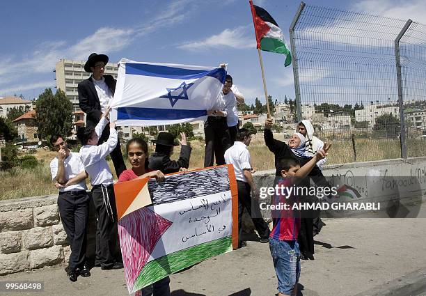 Ultra-Orthodox Israelis hold a national flag behind Palestinian women and children demonstrating against Jewish settlement in east Jerusalem's Sheik...