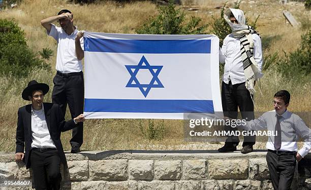 Ultra-Orthodox Israelis hold a national flag during a demonstration by Palestinians and Arab Israelis against Jewish settlement in east Jerusalem's...