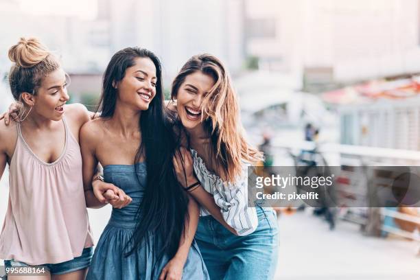 three young women walking and laughing - girlfriend stock pictures, royalty-free photos & images