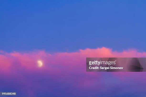 moon under pink cloud on blue sky - blue moon stock-fotos und bilder
