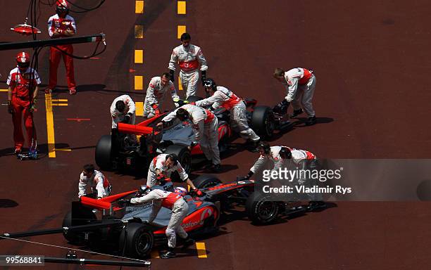 Lewis Hamilton of Great Britain and McLaren Mercedes and Jenson Button of Great Britain and McLaren Mercedes are pushed back into their garages...