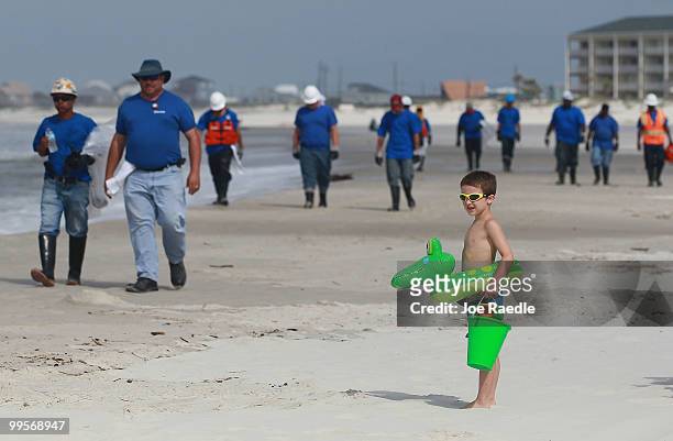 Logan Heyne waits for workers to pass by as they search the beach for tar balls to be picked up as they wash ashore from the Deepwater Horizon site...
