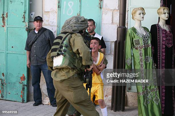 Israeli troops detain a Palestinian boy who thew a stone back at Jewish settlers during a protest near an Israeli army checkpoint in the occupied...