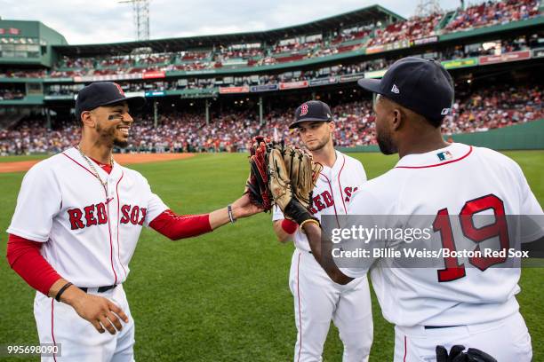 Little leaguers take the field with Andrew Benintendi, Jackie Bradley Jr. #19, and Mookie Betts of the Boston Red Sox high five before a game against...