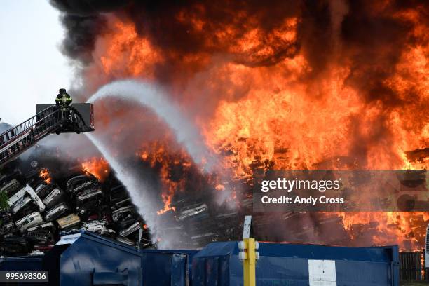 Adams County firefighters try to get control of a fire in a large pile of crushed vehicles near 5600 York St. July 10, 2018.