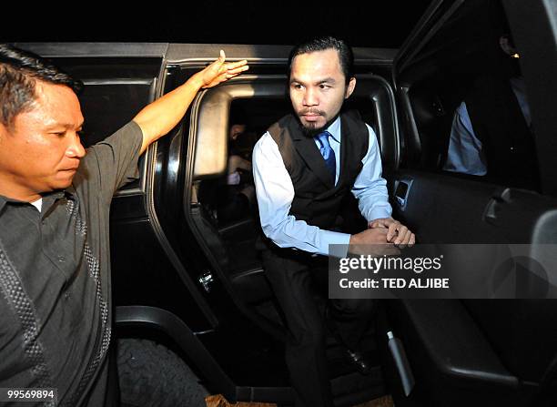 Philippine boxing superstar Manny Pacquiao steps out of a vehicle as he arrives for his victory party after winning a seat in the parliament, and to...