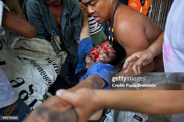 Red shirt protesters try to remove a man killed by Thai military as the violence in central part of the city escalates on May 15, 2010 in Bangkok,...