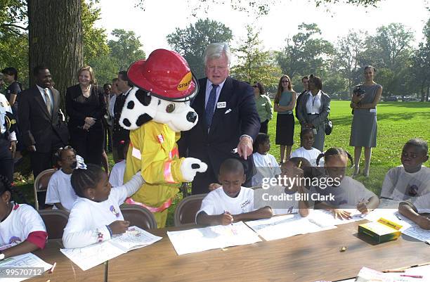 Sen Edward Kennedy along with Sparky watch over school kids as they draw Saprky in coloring books at the press conference to kick off fire prevention...