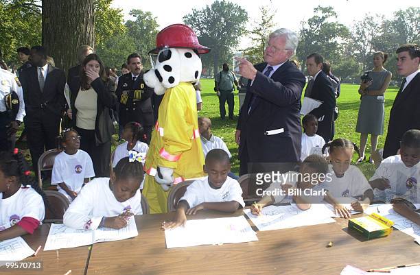 Sen Edward Kennedy along with Sparky watch over school kids as they draw Saprky in coloring books at the press conference to kick off fire prevention...
