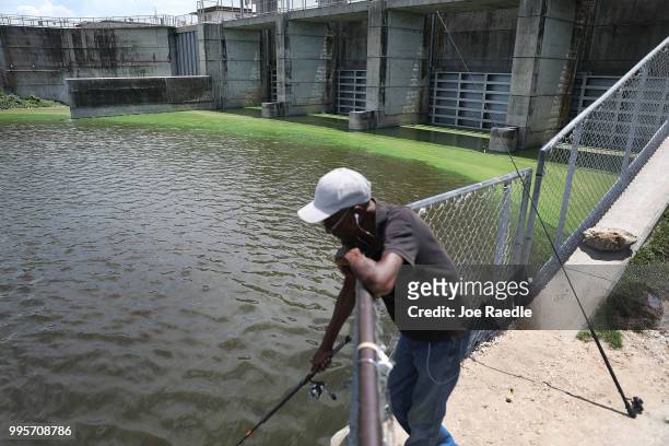 Al McLemore fishes near the green algae blooms that are seen at the Port Mayaca Lock and Dam on Lake Okeechobee on July 10, 2018 in Port Mayaca,...