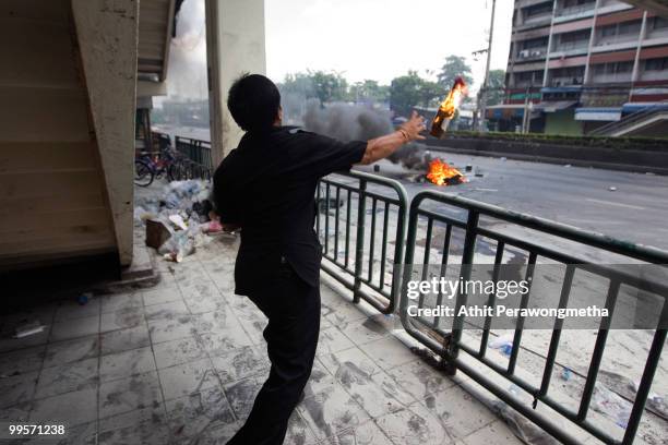 Anti-government protester 'Red Shirt' throws a molotov cocktail toward Thai security forces as the violence in central part of the city escalates on...