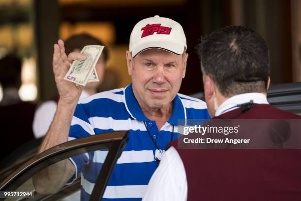 Michael Eisner, former chairman and chief executive officer of The Walt Disney Company, holds up money to tip the bellhop as he arrives at the Sun...