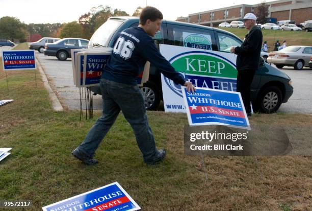 Dave Bernstein, a volunteer with the Sheldon Whitehouse campaign, puts up campaign signs as Jack Kendrick, a Chafee campiagn volunteer attaches...