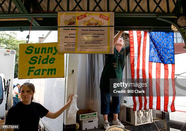 Valerie Fowler hangs an American Flag at the Sunnyside Farms' stand at Eastern Market in Washington on Saturday, July 28, 2007. Valerie is the wife...