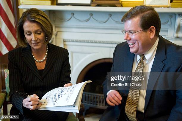 Speaker of the House Nancy Pelosi, D-Calif., autographs a copy of the Congressional Record for Bob Tapella, GPO's Public Printer, during a photo-op...