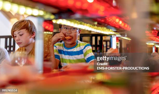 two 10 years old boys eating in sushi restaurant - 10 11 years old stock pictures, royalty-free photos & images