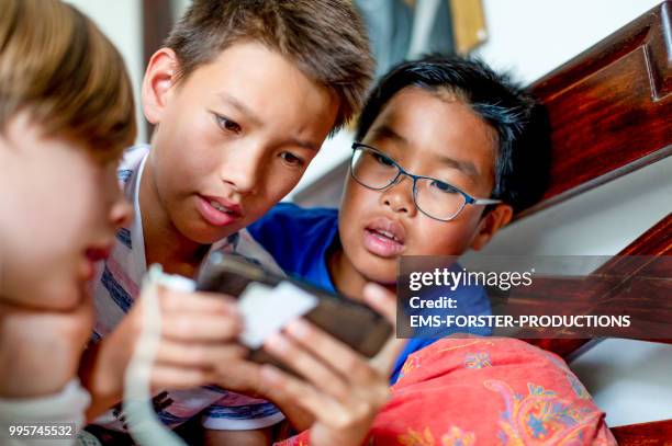 3 boys of diverse ethnicities gaming with smartphone - ems stockfoto's en -beelden