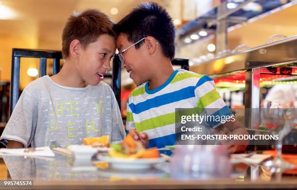 two brothers of different fathers in asian restaurant head to head - ems forster productions stock pictures, royalty-free photos & images