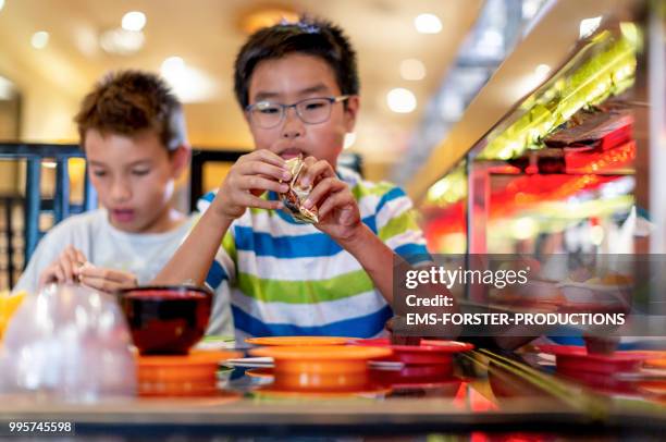 two brothers of different fathers in asian restaurant - sushi train stock pictures, royalty-free photos & images