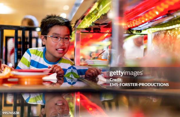 10 years old vietnamese boy in running sushi restaurant - ems stockfoto's en -beelden