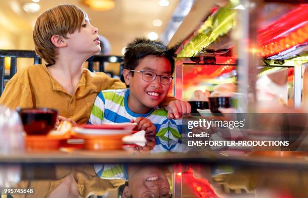 two 10 years old boys in sushi restaurant - ems stockfoto's en -beelden