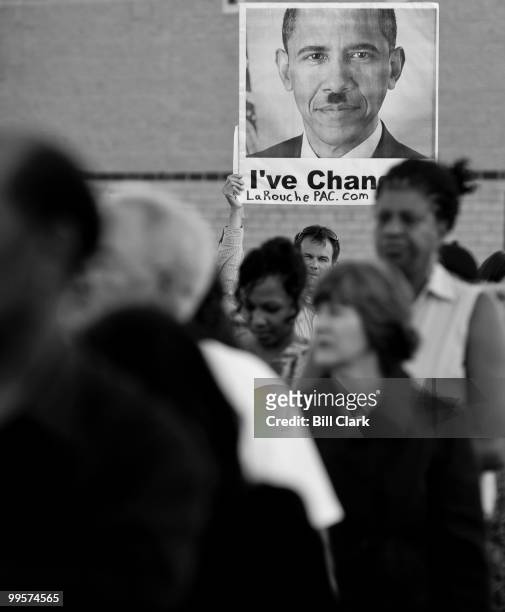 LaRouche suporter holds up a poster featuring President Obama with a Hitler mustache in the parking lot of North Point High School in Waldorf, Md.,...