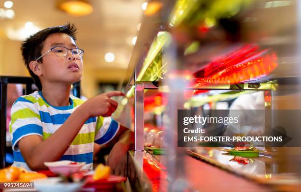 10 years old vietnamese boy in running sushi restaurant - ems photos et images de collection