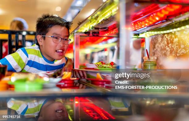 10 years old vietnamese boy in running sushi restaurant - ems stockfoto's en -beelden