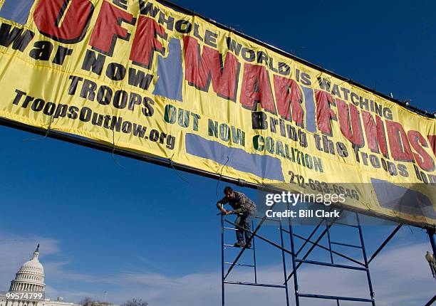 Walter Williams, of New York, N.Y., helps prepare the scaffolding for a second anti-war banner as The Troops Out Now Coalition sets up their...