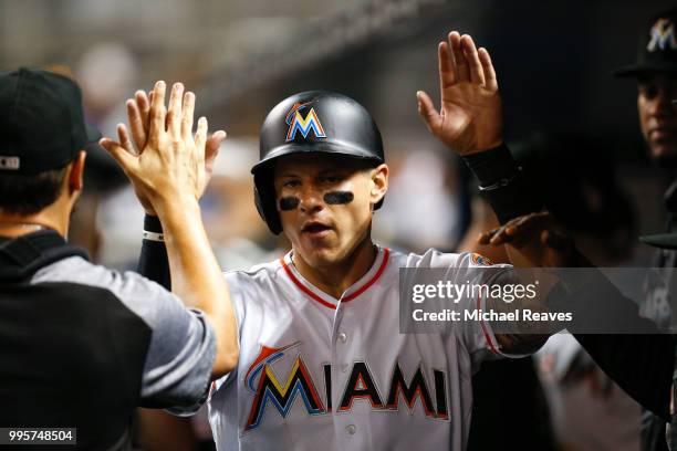 Derek Dietrich of the Miami Marlins high fives teammates after scoring in the first inning against the Milwaukee Brewers at Marlins Park on July 10,...
