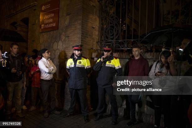 Catalan police of the "Mossos d'Esquadra" standing among people who have gathered outside Escola de Treball school in Barcelona, Spain, in the early...