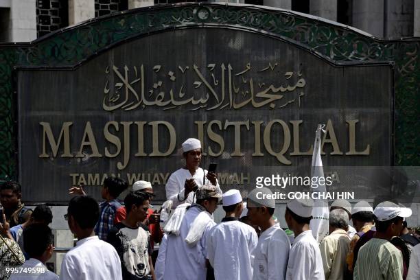 This picture taken on July 6, 2018 shows a group of Indonesian Muslim men gathering to take photos at the Istiqlal mosque in Jakarta. - A small...