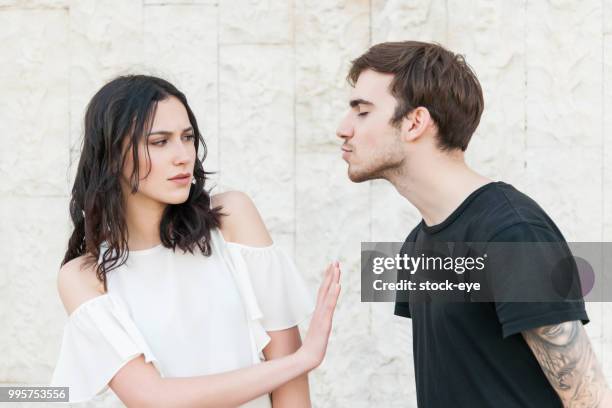 hombre joven tratando de besar a una mujer joven - kissing fotografías e imágenes de stock