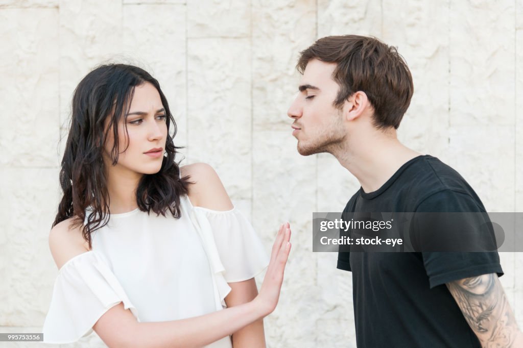 Young man trying to kiss a young woman